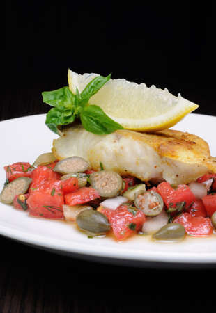 slice of baked fish perch with vegetable garnish and lemonの写真素材