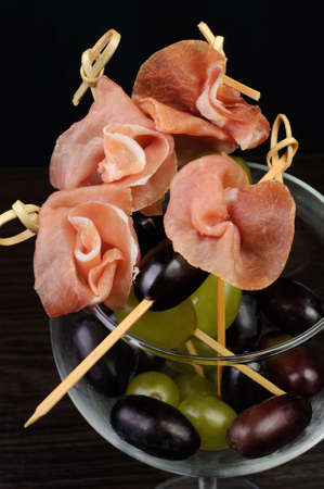 Appetizer of ham with grapes on a skewer in the glassの写真素材