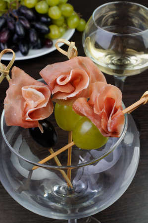 Appetizer of ham with grapes on a skewer in the glassの写真素材