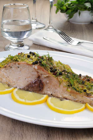 Baked piece of carp with lemon dill sauce on a plate