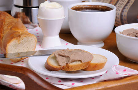 A slice of toast spread with liver pate for breakfast and a cup of coffee on a trayの写真素材