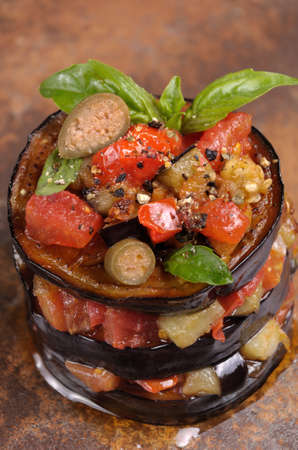 Appetizer of fried eggplant with diced tomatoes, capers, flavoured spicesの写真素材