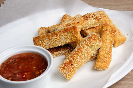 Slices of toast fried in breaded with cheese , sesame and sauce on a paper  in   plate の写真素材