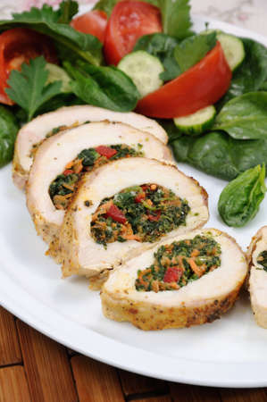 Slices of chicken breast stuffed with spinach, carrot, pepper, tomato on a plate     garnish of vegetablesの写真素材