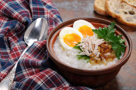 Rice porridge ginger congee with egg, chicken, crispy shallots and parsleyの写真素材