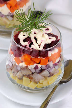 Salad of chopped herring with onions, potatoes, beets, carrots, seasoned with yogurt sauce in a glassの写真素材