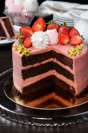 Chocolate strawberry cake decorated with berries, meringue and pistachios in a cutの写真素材