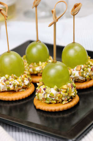 Canape  of cottage cheese cushions  in pistachios with grapes on crackerの写真素材