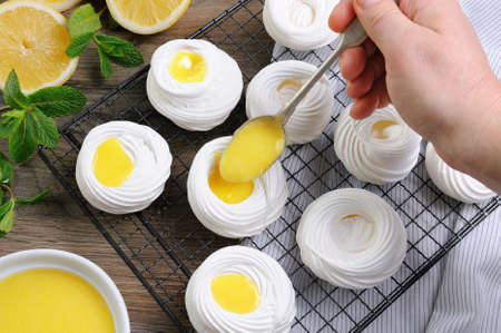 Filling with a lemon kurd, a delicate, crispy mini-dessert "Pavlova" on the rackの写真素材