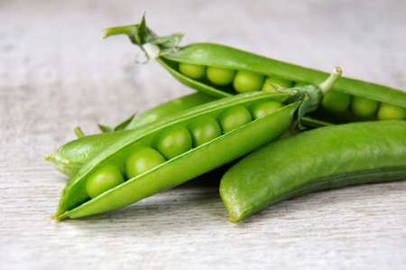 Pods of fresh green peas on a wooden background closeupの写真素材
