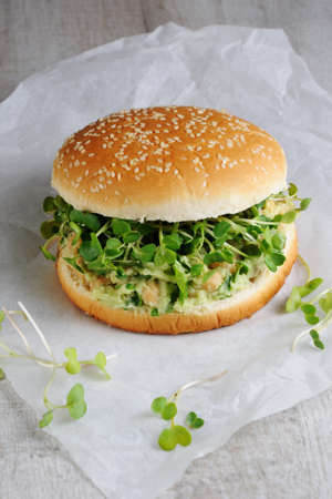 A vegetarian burger made from a gluten-free bun with chickpeas, avocado and herbs, radish sprouts. A quick and healthy lunch idea that you feel energized throughout the day.の写真素材