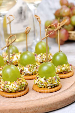 Canape  of cottage cheese cushions  in pistachios with grapes on cracker