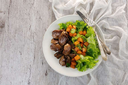 Fried chicken liver with vegetable garnish, baked pumpkin in lettuce leavesの写真素材