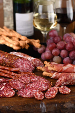 Antipasto. Dish with sausage, dried ham, salami, crispy grissini with grapes. A meat appetizer is a...