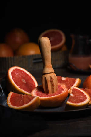 Slices of fresh grapefruit prepared for making fresh squeezed juice on a platter, dark backgroundの写真素材
