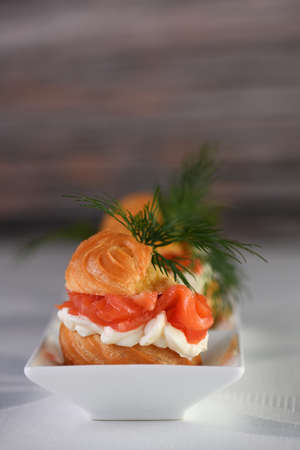 Profiteroles stuffed with cream cheese and salmon, decorated with a sprig of dill. Close-up