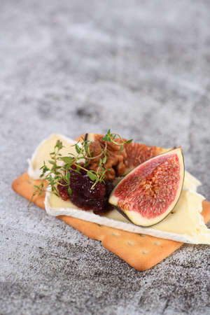 Cracker with a slice of camembert, jam, figs and nuts. A great snack idea for a holiday, picnic or party.の写真素材