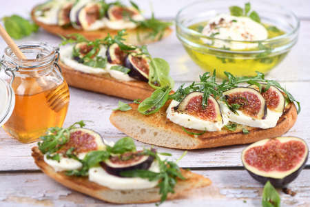 Bruschetta with mozzarella, arugula and figs, seasoned with honey and spicesの写真素材
