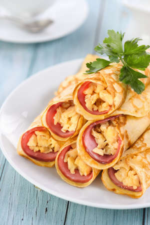 Homemade thin pancakes with a slice of ham and scrambled eggs, stacked in a stack, on the table. Great breakfast idea.の写真素材