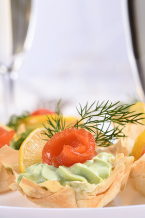 Avocado whipped with soft cheese cream into the most delicate mousse, a slice of salmon and lemon. Served in crispy baskets with phyllo dough baked in the oven. The perfect appetizer for a holiday menuの写真素材