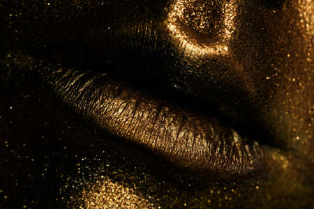 The lips of a young girl covered with gold paintの写真素材