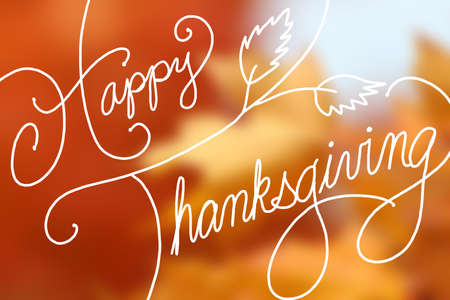Happy Thanksgiving text design on blurred orange maple leavesの写真素材