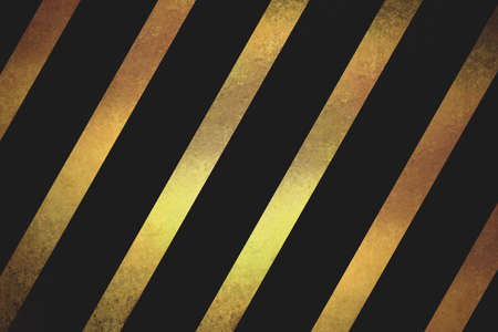 shiny gold textured ribbon slanted diagonally in striped pattern on black backgroundの写真素材
