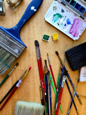 Artist brushes and paints in top view design, art studio table with pans of watercolor ready for painter, creative workplace or workshopの写真素材