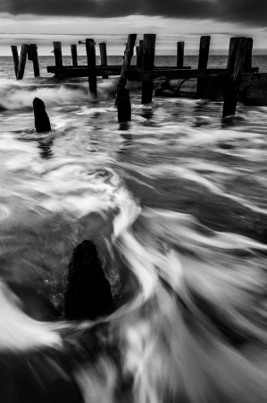Waves swirl around pier pilings in the Delaware Bay at sunset, seen from Sunset Beach, Cape May, New Jersey.の写真素材