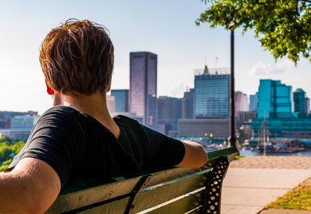 Man sitting on bench, looking toward the Baltimore Skyline from Federal Hill.の写真素材