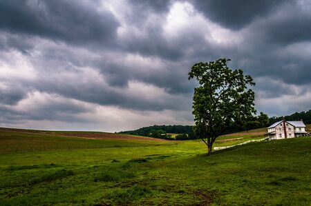 Dark stormy sky over trees and a house in York County, Pennsylvania.の写真素材