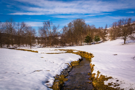 Small stream through a snow covered farm field in rural Carroll County, Maryland.の写真素材
