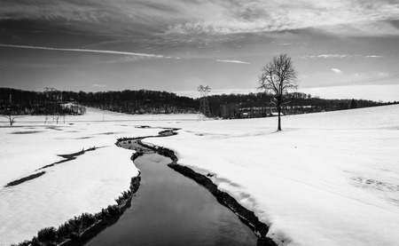 Small stream through a snow covered farm field in rural Carroll County, Maryland.の写真素材