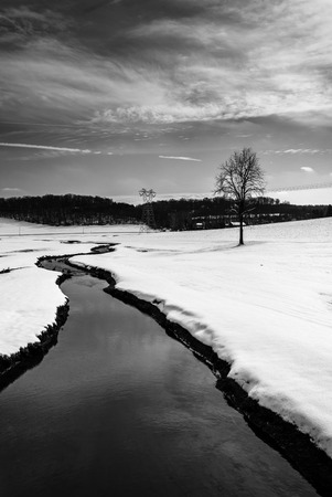 Small stream through a snow covered farm field in rural Carroll County, Maryland.の写真素材