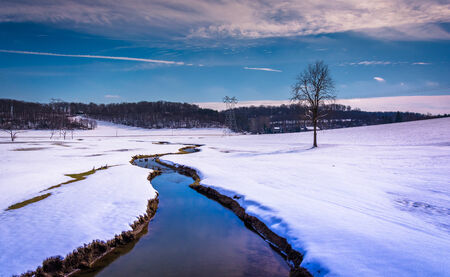 Small stream through a snow covered farm field in rural Carroll County, Maryland.の写真素材