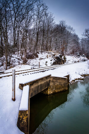 Snow covered railroad bridge over a creek in rural Carroll County, Maryland.の写真素材