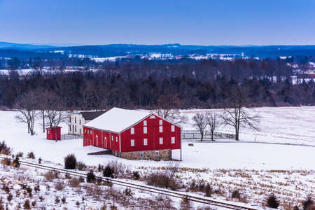 View of a red barn in a snow-covered field in Gettysburg, Pennsylvania.のeditorial素材