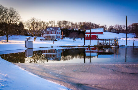 House and barn reflecting in a semi-frozen pond in rural York County, Pennsylvania.の写真素材