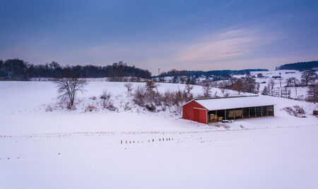 Red barn on a snow-covered farm in rural York County, Pennsylvania.の写真素材