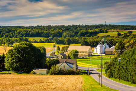 Country road and view of silo and barn on a farm in rural York County, Pennsylvania.の写真素材