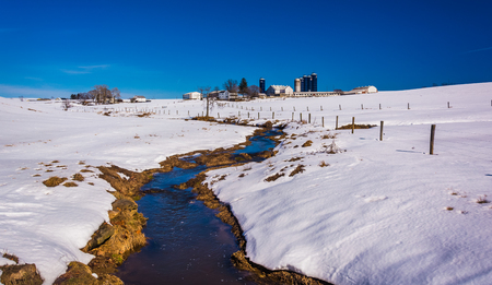 Stream through a snow covered farm field in rural Lancaster County, Maryland.の写真素材
