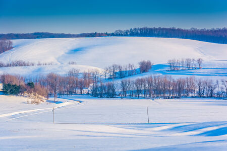 View of snow covered rolling hills and farm fields in rural York County, Pennsylvania.の写真素材