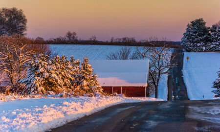 Winter view of a country road and red barn at sunset in rural York County, Pennsylvania.の写真素材