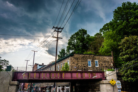Storm clouds over a railroad bridge and buildings in Ellicott City, Maryland.のeditorial素材