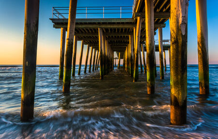Fishing pier and waves on the Atlantic Ocean at sunrise in Ventnor City, New Jersey.の写真素材