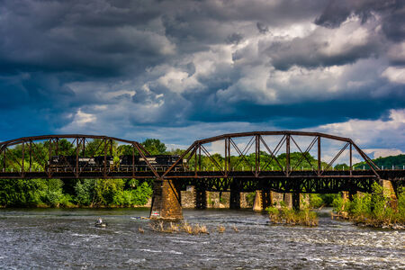 Storm clouds over a train bridge and the Delaware River in Easton, Pennsylvania.の写真素材