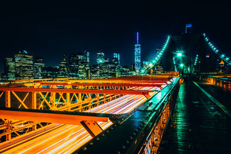 The Manhattan Skyline and traffic on the Brooklyn Bridge at night, New York.の写真素材