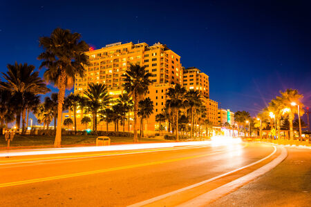 Traffic moving past a hotel and palm trees on Coronado Drive at night, in Clearwater Beach, Florida.のeditorial素材