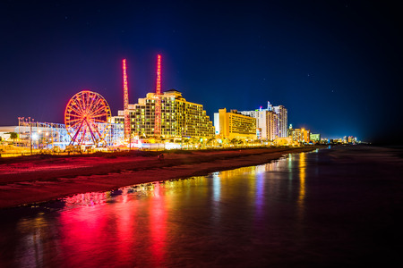 View of hotels and rides along the boardwalk at night from the fishing pier in Daytona Beach, Florida.の写真素材