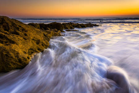 Rocks and waves in the Atlantic Ocean at sunrise in Palm Coast, Florida.の写真素材